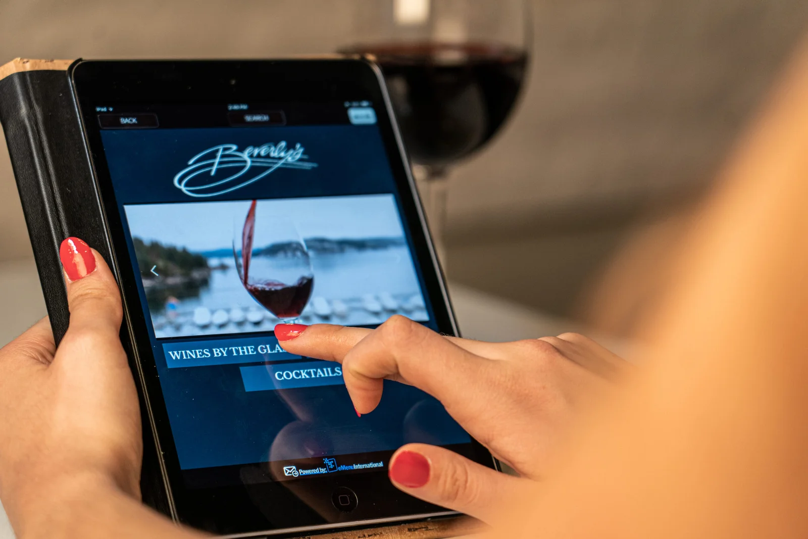 A guest using a tablet-based digital wine menu at Beverly's restaurant, selecting wines by the glass