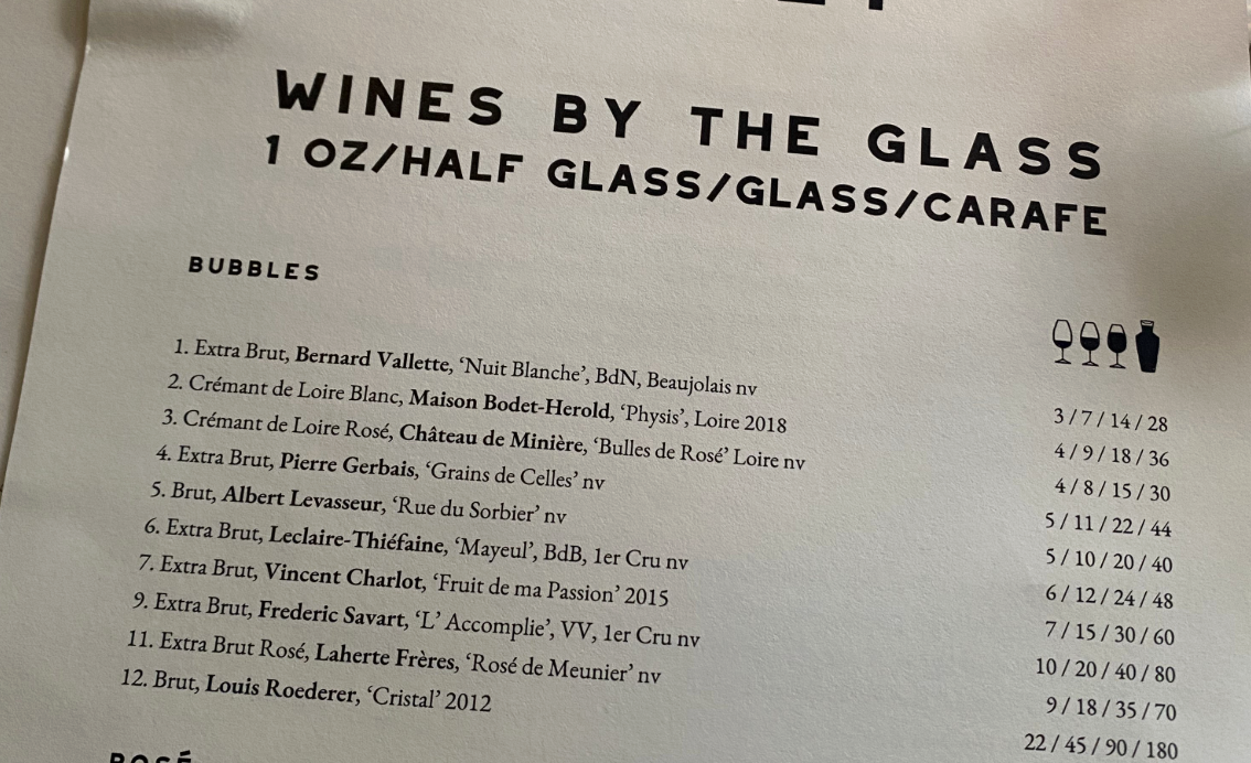 A wine menu showing multiple serving size options including 1oz tastes, half glasses, full glasses, and carafes